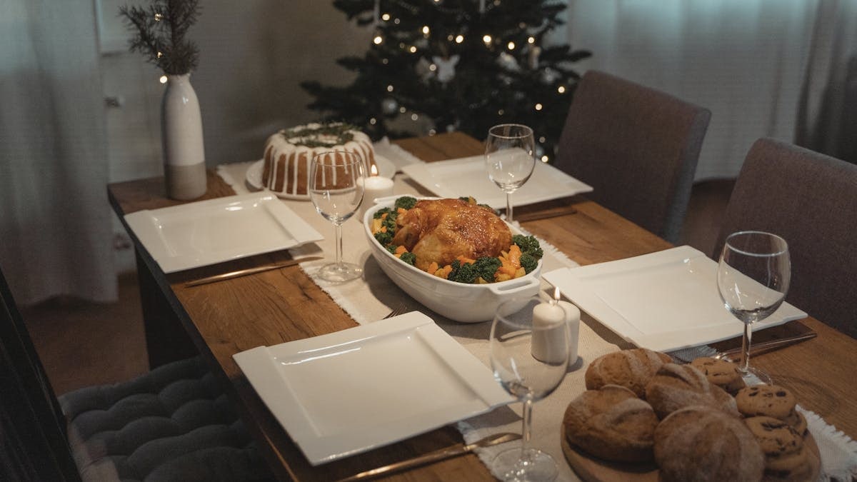 A beautifully set holiday dinner table with roast chicken and desserts, evoking warmth and celebration.